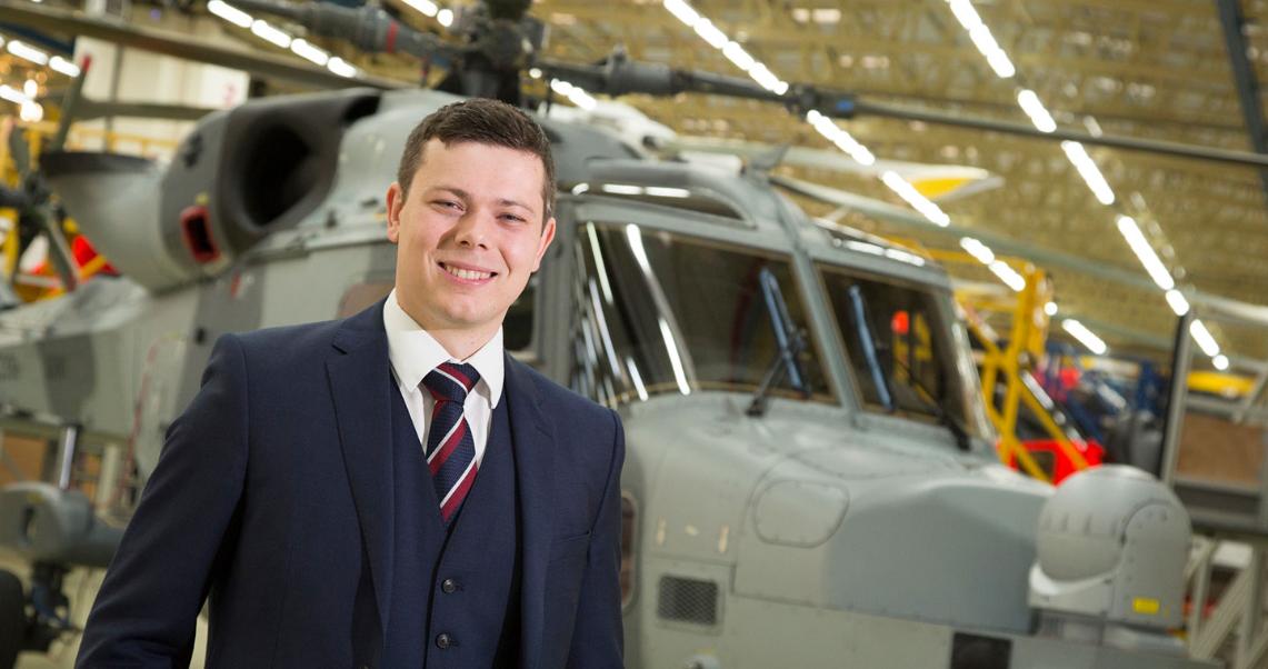Daniel Young stands in front of a helicopter at Leonardo